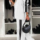 Stylish woman in a gray lapel collar top and wide-leg pants set with black stripes, accessorized with a chic handbag.