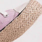 Close-up of a pink lace-up sneaker showcasing a stylish woven espadrille sole for a trendy summer look.