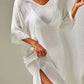 Woman wearing a white slit v-neck flounce sleeve cover-up, showcasing sheer and backless design with tied detail.