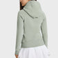 Stylish back view of a woman in a light green hooded sports jacket paired with a white skirt, perfect for outdoor activities.