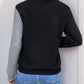 Woman in black decorative button contrast long sleeve sweatshirt with quilted design and grey sleeve, standing outdoors.