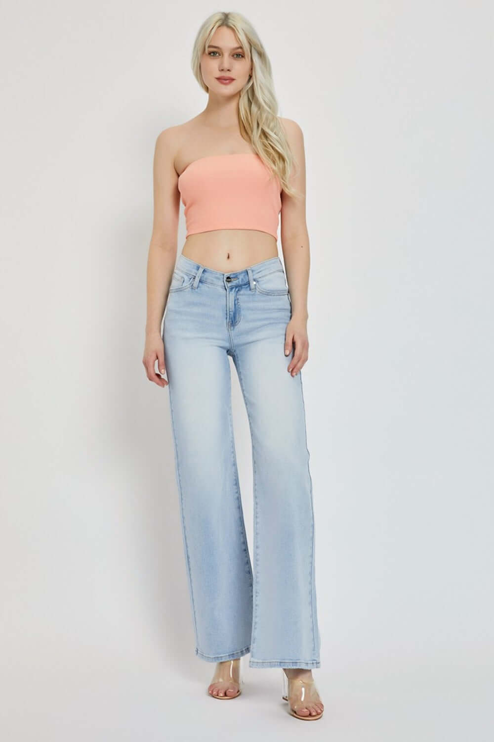 Woman wearing RISEN Full Size Wide Leg V Dipped Front Waist Jeans and peach tube top, showcasing modern and flattering jean style