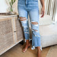 Woman wearing Bella Road Distressed Raw Hem Jeans with Pockets, moderate stretch denim, styled with a casual outfit indoors.