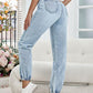 Woman wearing Bella Road High Waist Jeans with Pockets, light blue denim, standing in living room with floral decor.