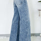 Woman wearing high waist wide leg jeans with back pockets, slightly stretchy denim, and a comfortable fit. Cotton blend material.