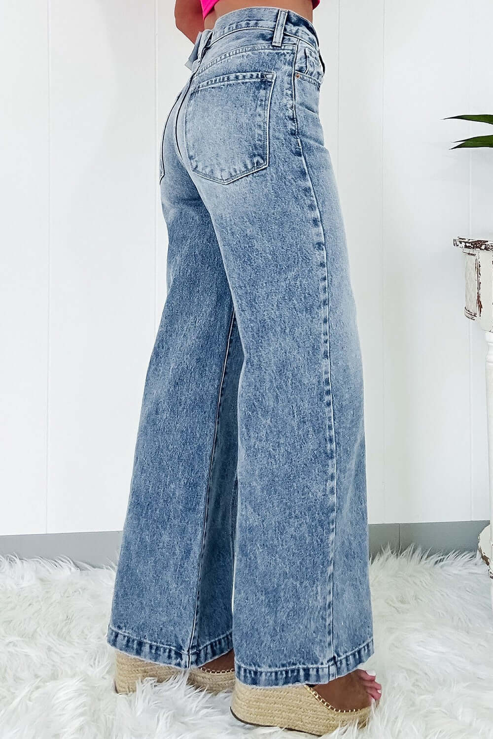 Woman wearing high waist wide leg jeans with back pockets, slightly stretchy denim, and a comfortable fit. Cotton blend material.