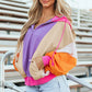 Woman wearing drawstring color block zip up long sleeve hoodie with vibrant colors and denim shorts.