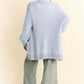 Woman in a cozy light blue cardigan with long sleeves and ribbed hem, paired with gray pants from the back.