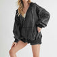 Model showcasing Aemi+Co Exposed Seam Zip Up Drawstring Hooded Jacket in black, styled for a trendy casual look.