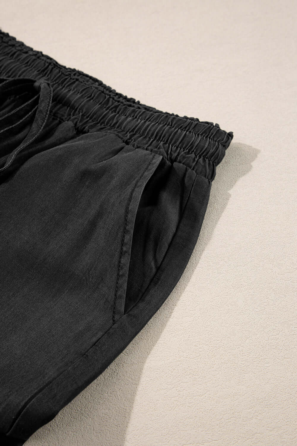 Close-up of the drawstring waist and pockets of Bella Road Black Wide Leg Jeans on a light background.