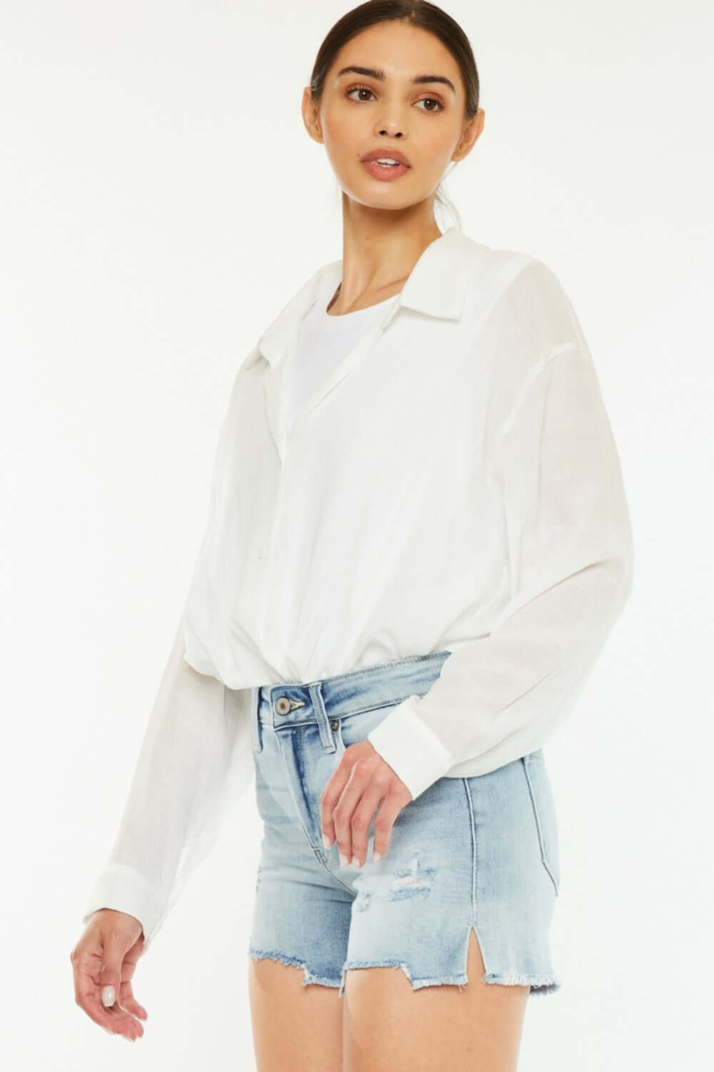 Woman wearing high-rise side slit denim shorts and a white blouse, showcasing a stylish summer outfit perfect for casual and dressed-up occasions