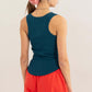 Woman wearing a teal Ribbed Scoop Neck Racerback Tank paired with red pants, showcasing the racerback design and ribbed texture.