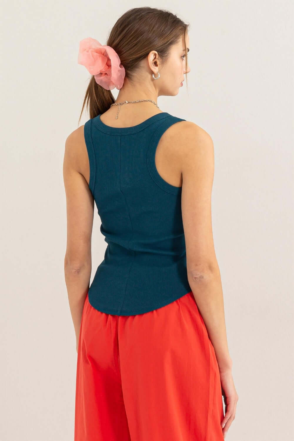 Woman wearing a teal Ribbed Scoop Neck Racerback Tank paired with red pants, showcasing the racerback design and ribbed texture.