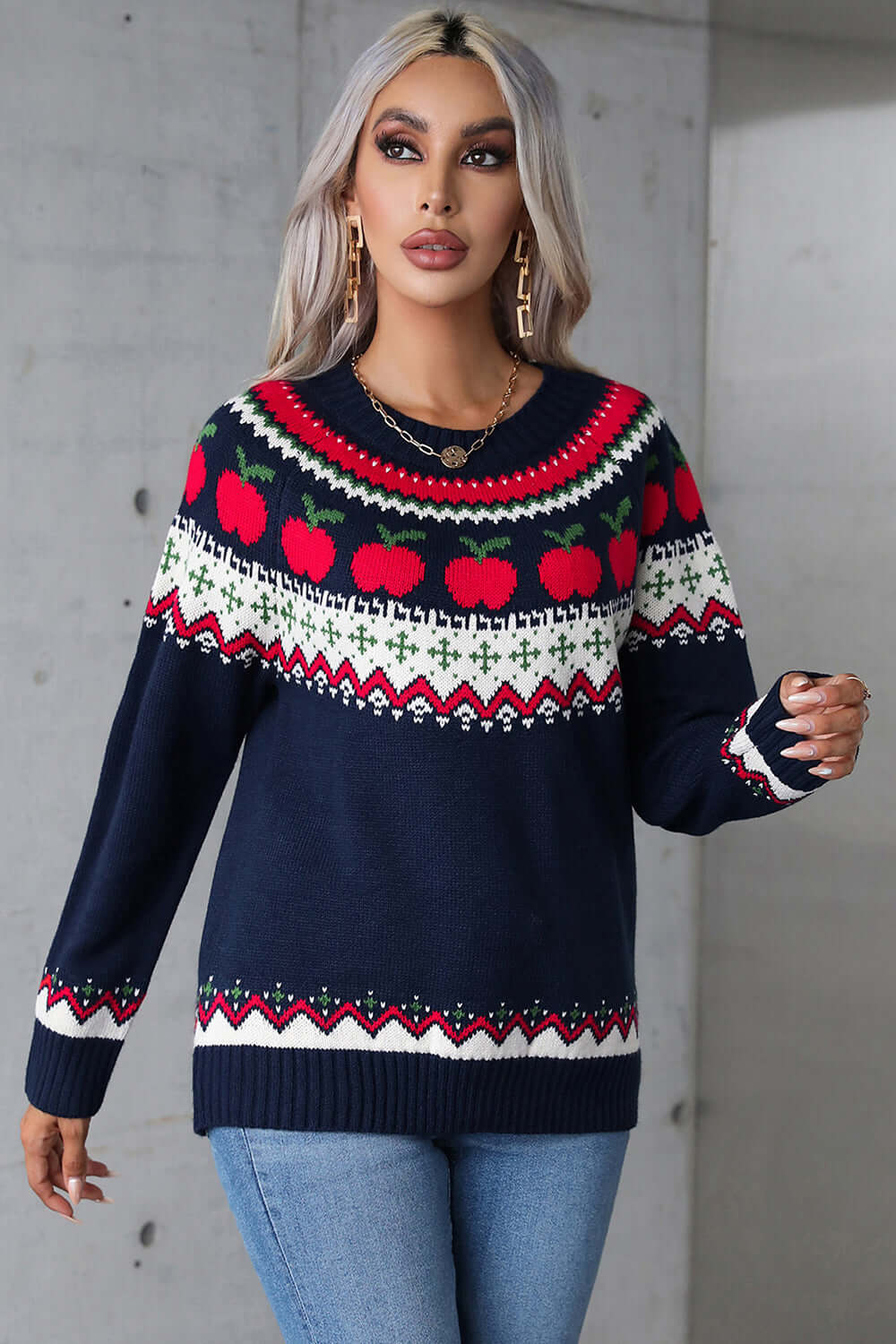 Woman wearing angel wings graphic round neck long sleeve sweater with apple design, paired with jeans.