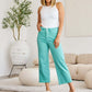 Woman wearing RFM Jeans Crop Chloe Full Size Tummy Control High Waist Raw Hem Jeans in a stylish living room