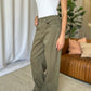 Woman wearing RFM High Rise Garment Dye Wide Leg Jeans in green, paired with a white top, standing indoors.