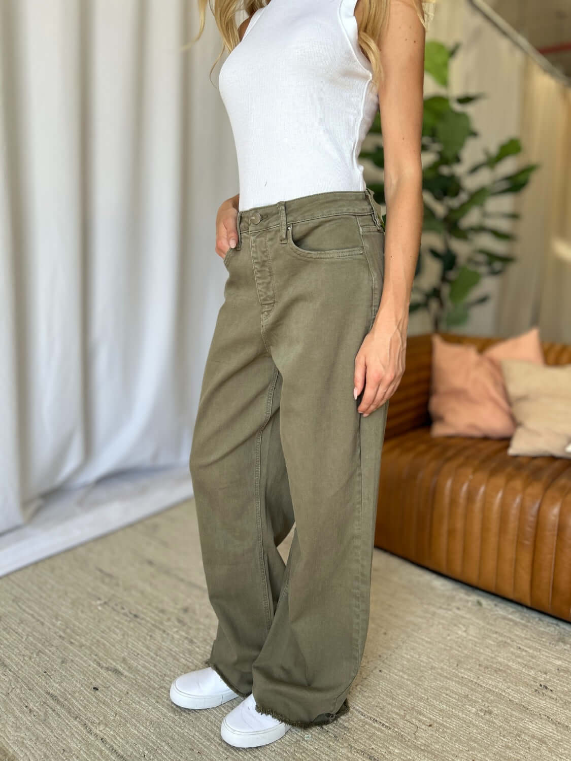 Woman wearing RFM High Rise Garment Dye Wide Leg Jeans in green, paired with a white top, standing indoors.