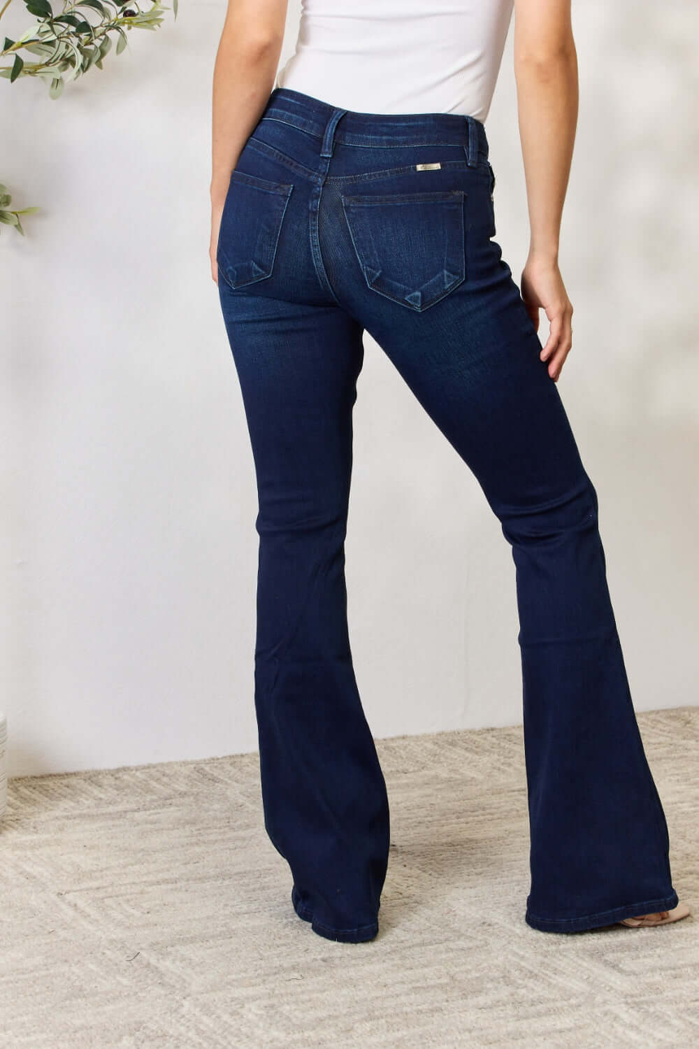 Woman wearing Mid Rise Flare Jeans, showcasing a timeless, non-distressed silhouette with a comfortable stretch fit.