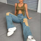 Woman wearing Bella Road Distressed Wide Leg Jeans with Pockets and sneakers sitting on floor in edgy fashion pose