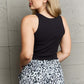 Woman wearing Bow Down Sleeveless Ruffle Crop Top with animal print pants, shown from the back against a gray background