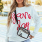 Woman wearing Bella Road Game Day Round Neck Long Sleeve Sweatshirt with "Game Day" design, paired with denim shorts and clear crossbody bag