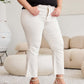 Woman wearing high waist white jeans with raw hem and wedge sandals in a stylish indoor setting.