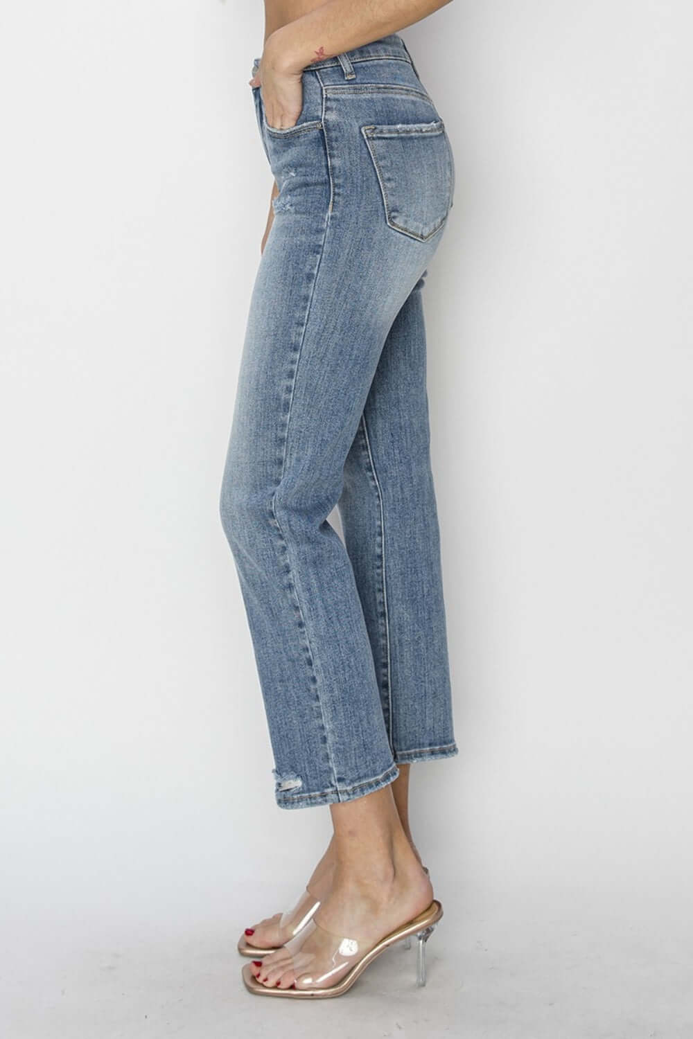 High Waist Distressed Cropped Jeans by Risen Jeans side view with clear heels, showcasing flattering silhouette and rugged details.