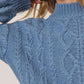 Close-up of a cozy blue cable-knit mock neck sweater with dropped shoulders, showcasing its stylish texture and relaxed fit.