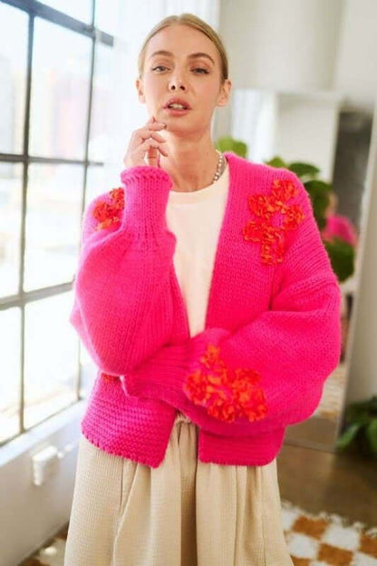 Model wearing a vibrant pink floral applique open front cardigan, styled effortlessly for a chic look.