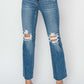 Woman wearing high rise distressed ankle jeans, Risen Jeans, with trendy ripped details, perfect for casual or night out styling.