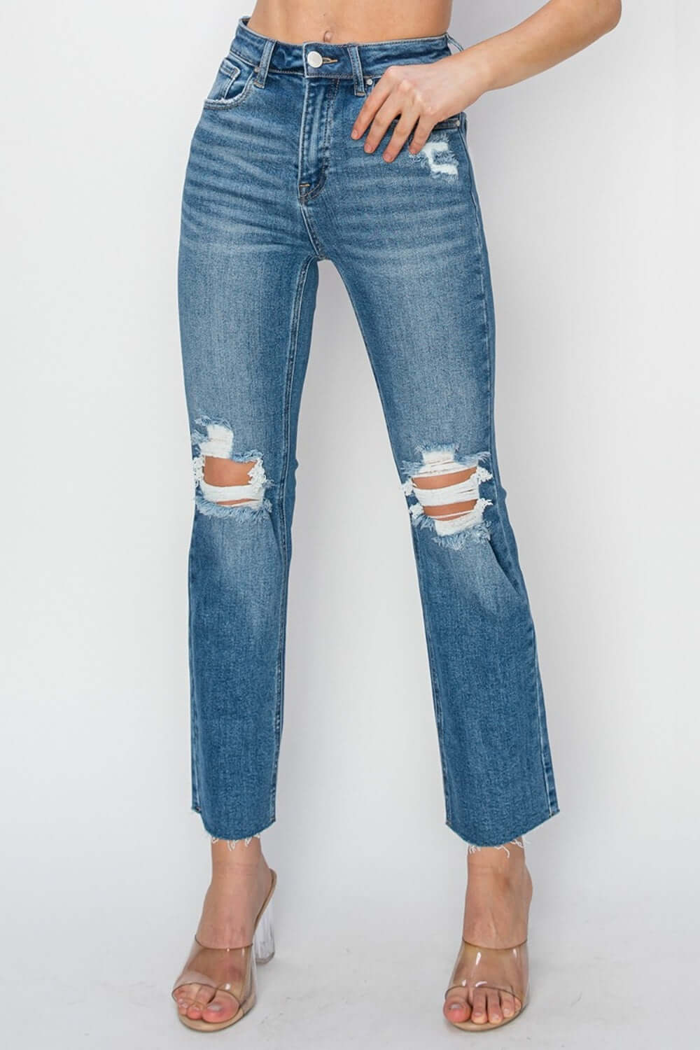 Woman wearing high rise distressed ankle jeans, Risen Jeans, with trendy ripped details, perfect for casual or night out styling.