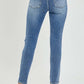 Woman modeling Risen Jeans High Rise Knee Distressed Skinny Jeans back view showing pockets and hem details.