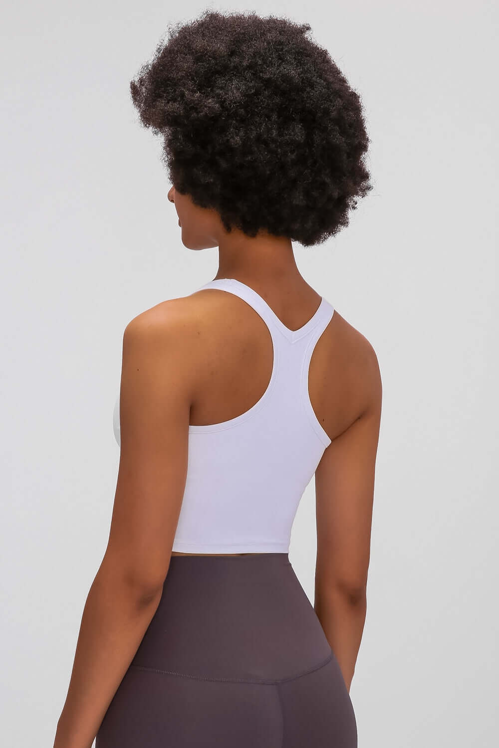 Back view of a woman wearing a white Millennia Racerback Sports Bra, showcasing its stylish design and slim fit.