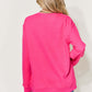 Back view of woman wearing a vibrant pink letter graphic long sleeve sweatshirt with blue jeans