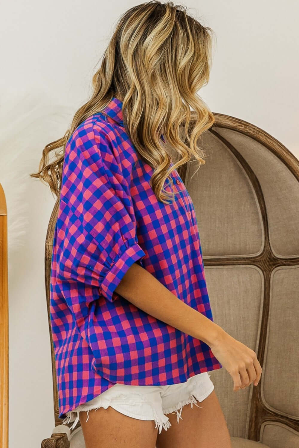 Woman wearing a Plaid Button Up Dolman Sleeve Shirt with blue and pink checkered pattern, paired with white frayed shorts.