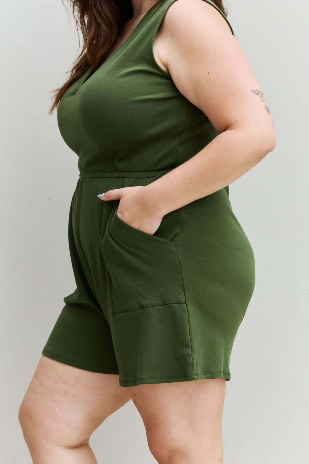 Woman wearing Forever Yours V-Neck Sleeveless Romper in Army Green with pockets, side view showing comfortable fit