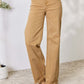 Woman wearing Risen Jeans fringe hem wide leg jeans in beige, showing high-waisted fit and slightly stretchy material, casual chic style.