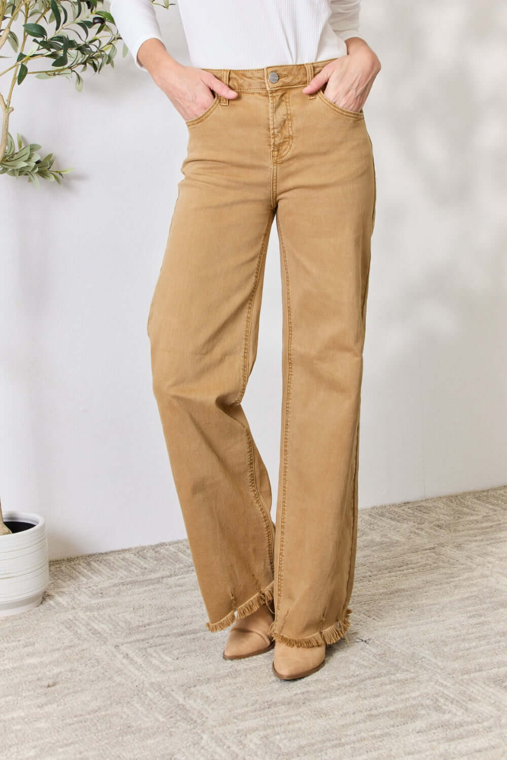 Woman wearing Risen Jeans fringe hem wide leg jeans in beige, showing high-waisted fit and slightly stretchy material, casual chic style.