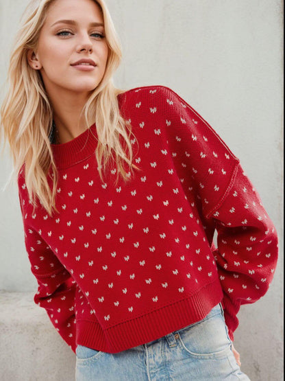 Woman wearing a red Bella Road sweater with a heart pattern and long sleeves, paired with jeans, showcasing a stylish fall look.