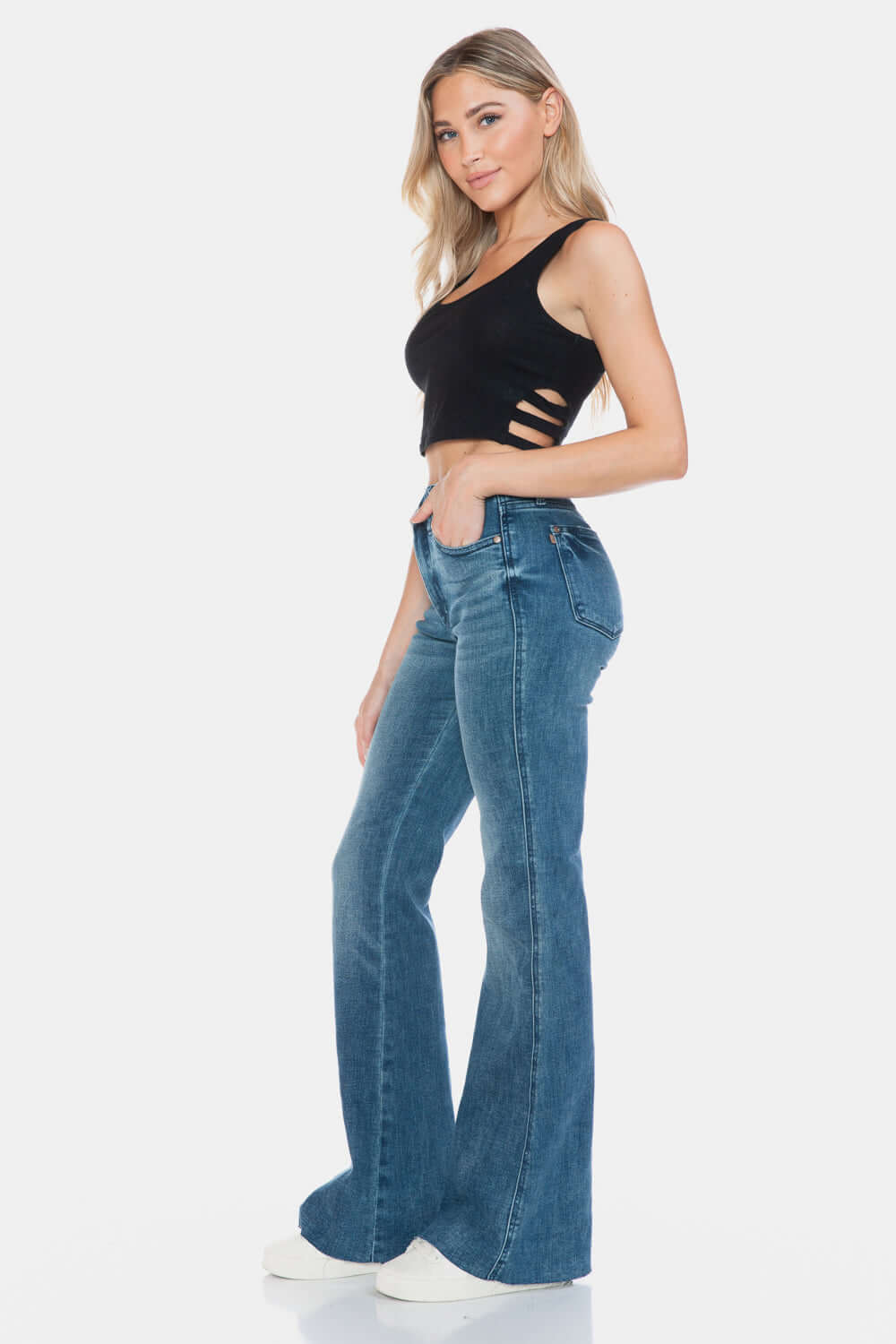 Woman wearing Judy Blue Full Size Tummy Control Cut Hem Flare Jeans with vintage wash and black top, showcasing a stylish silhouette