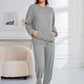 Woman wearing gray Bella Road Dropped Shoulder Long Sleeve Hoodie and Pants Set in cozy room.