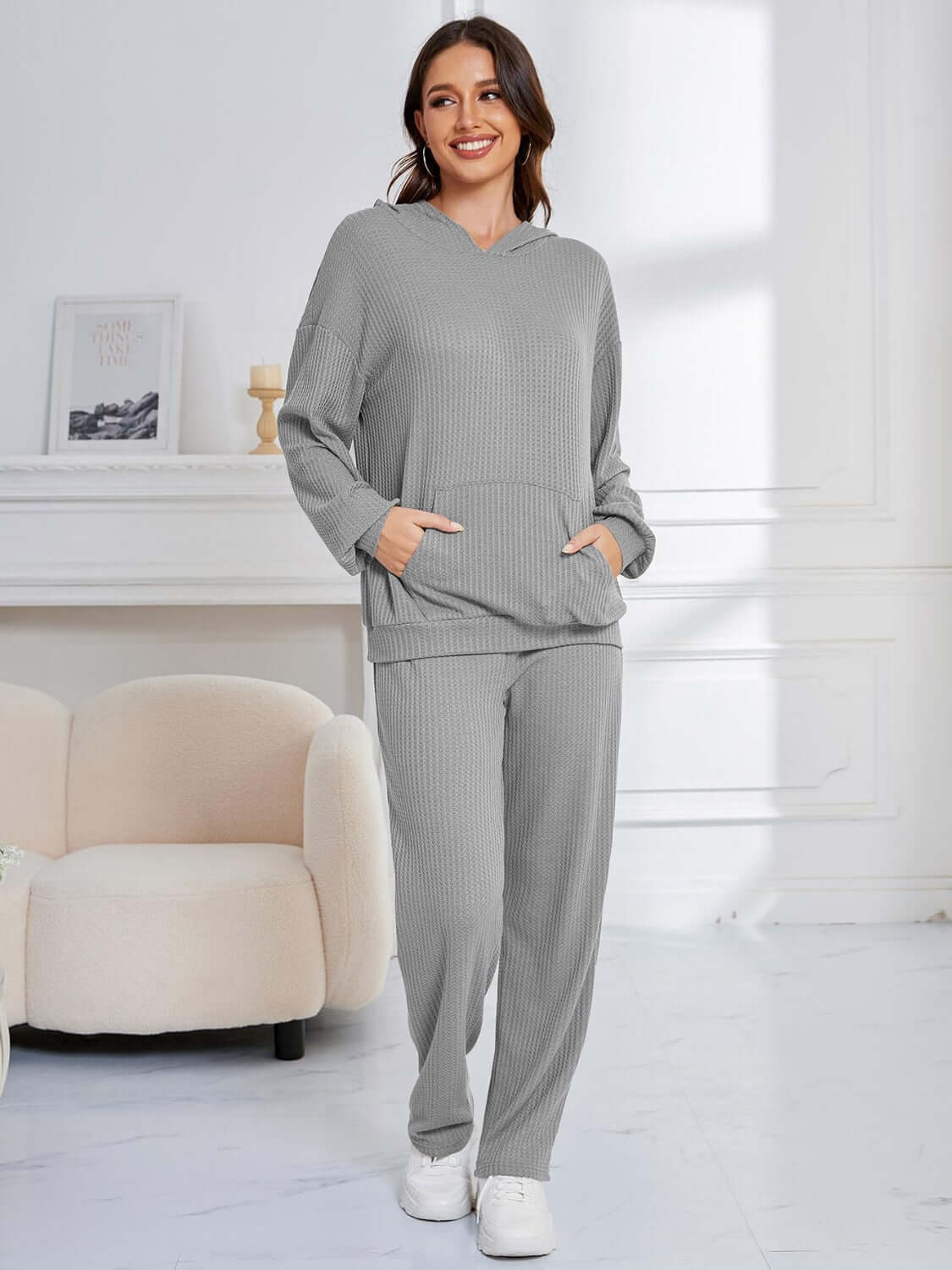 Woman wearing gray Bella Road Dropped Shoulder Long Sleeve Hoodie and Pants Set in cozy room.