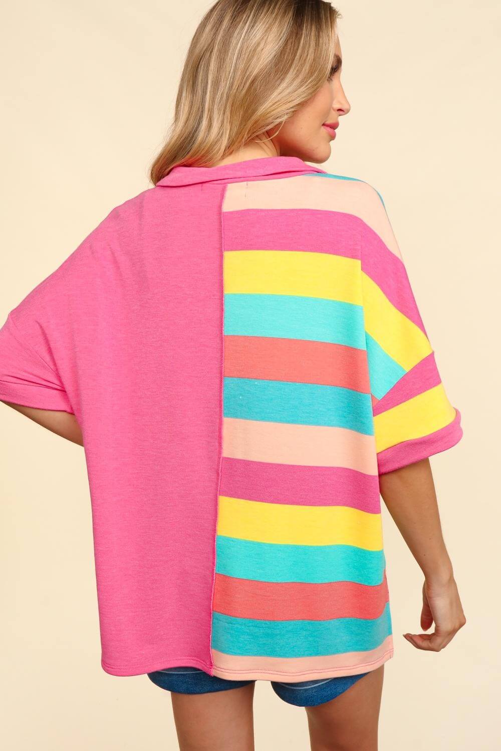 Woman wearing exposed seam short sleeve half-striped t-shirt in pink, yellow, teal, and coral colors, viewed from the back