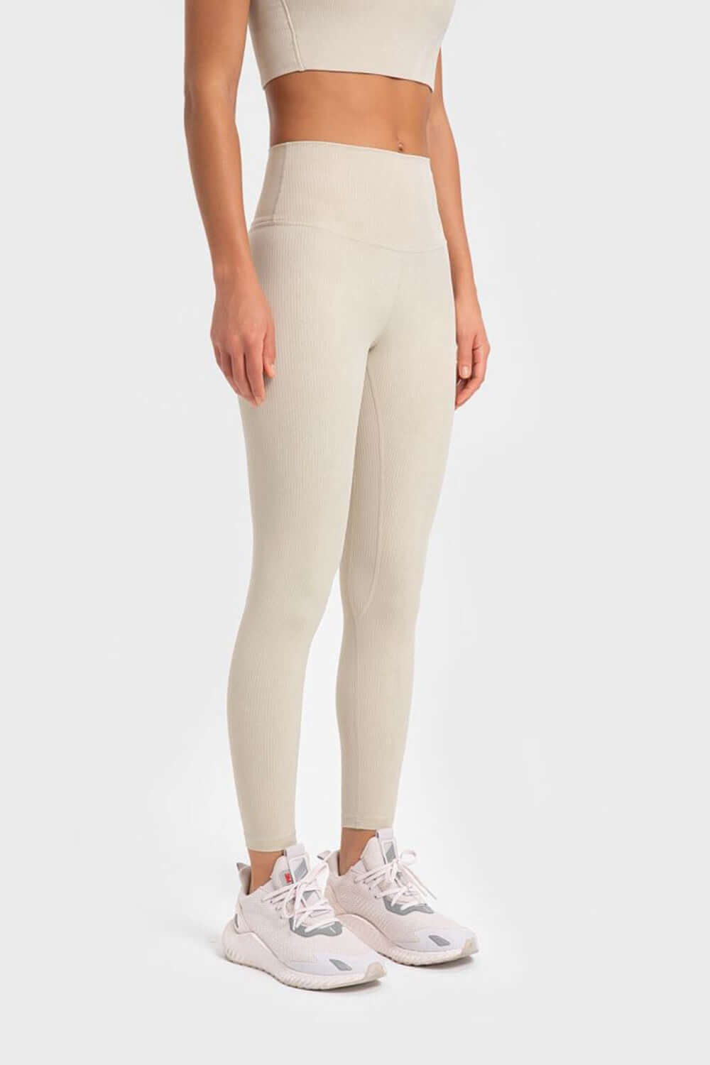 Model showcasing Millennia Highly Stretchy Wide Waistband Yoga Leggings in light beige with matching top and stylish sneakers.