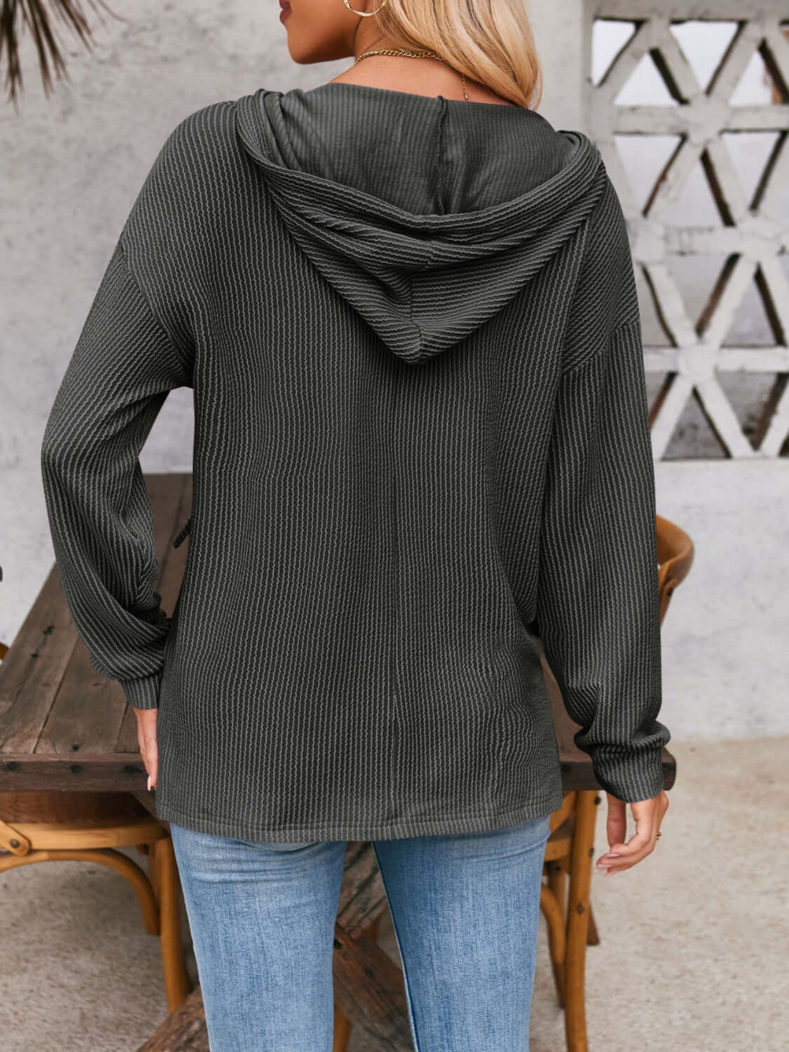 Woman wearing a dark gray drawstring dropped shoulder long sleeve hoodie, view from the back. Perfect casual wear.