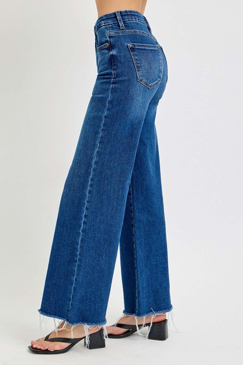 High rise wide leg jeans with raw hem, showcasing flattering silhouette and pocket detail. Perfect for chic fashion-forward styles.