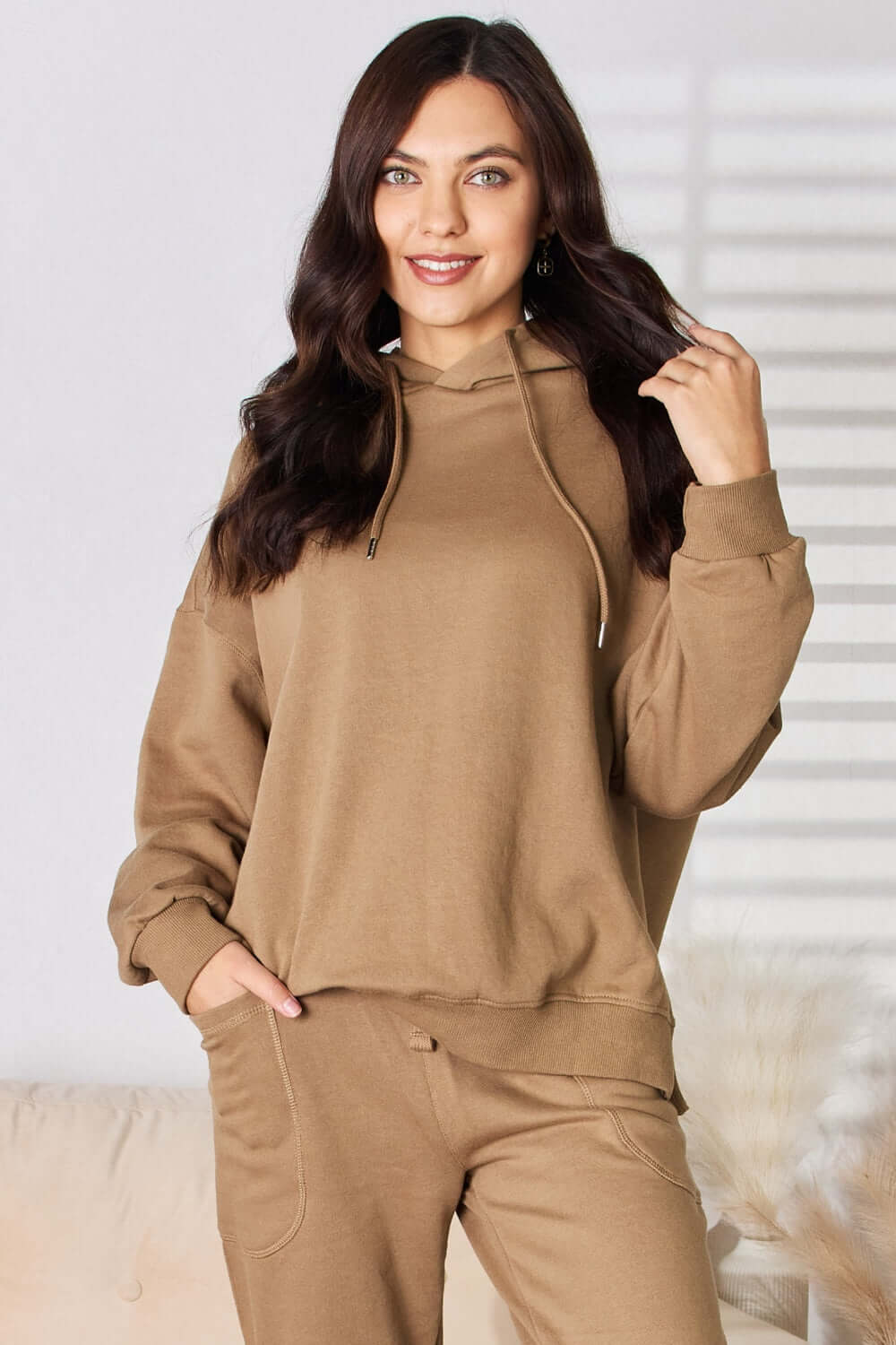 Woman wearing RISEN drawstring drop shoulder long sleeve hoodie in light brown, showcasing cozy and fashionable casual outfit.