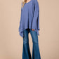 Woman wearing Ces Femme Asymmetrical Long Sleeve Top with hi-low hem, paired with flared jeans for a chic and modern look.