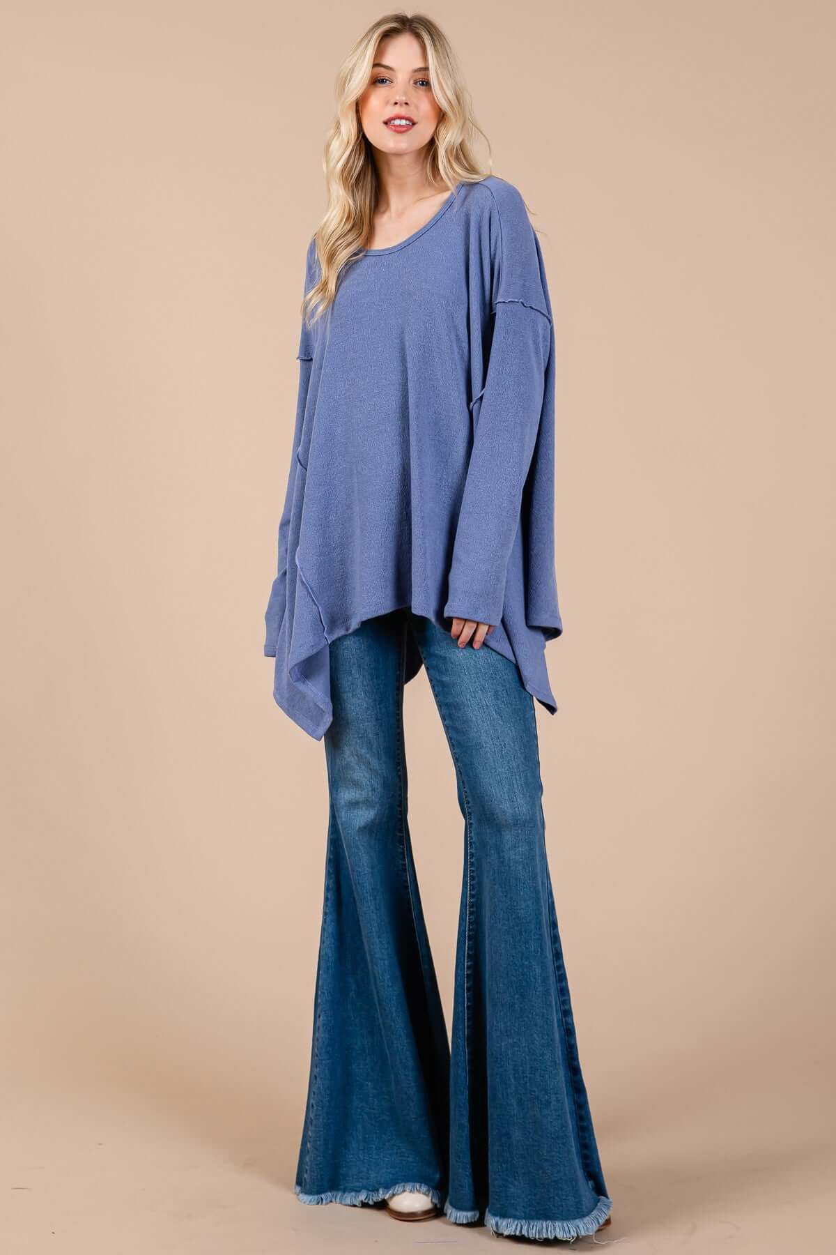 Woman wearing Ces Femme Asymmetrical Long Sleeve Top with hi-low hem, paired with flared jeans for a chic and modern look.