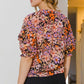 Woman wearing Floral Tie Neck Ruffled Blouse with colorful floral print and ruffled details from the back.